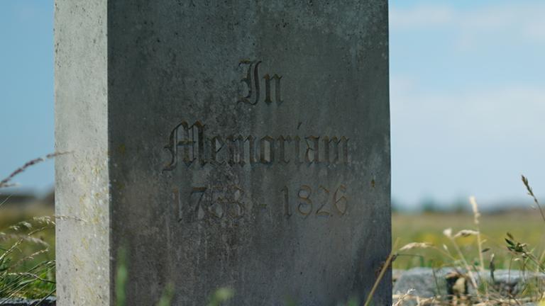 "Lost Places – Geheime Welten - Verlorenes Empire": Ein alter Grabstein auf einer Wiese.