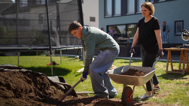 Frau und Junge bei der Gartenarbeit.