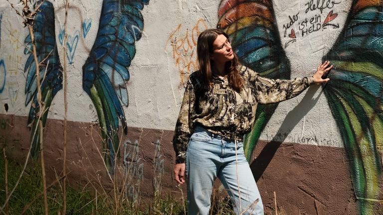 Frau vor Haus mit Graffitis. 