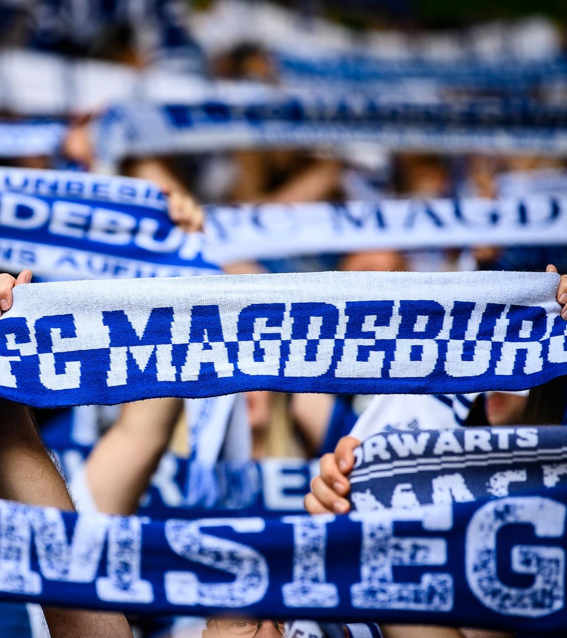 Fans des 1. FC Magdeburg halten ihre Fan-Schals hoch.