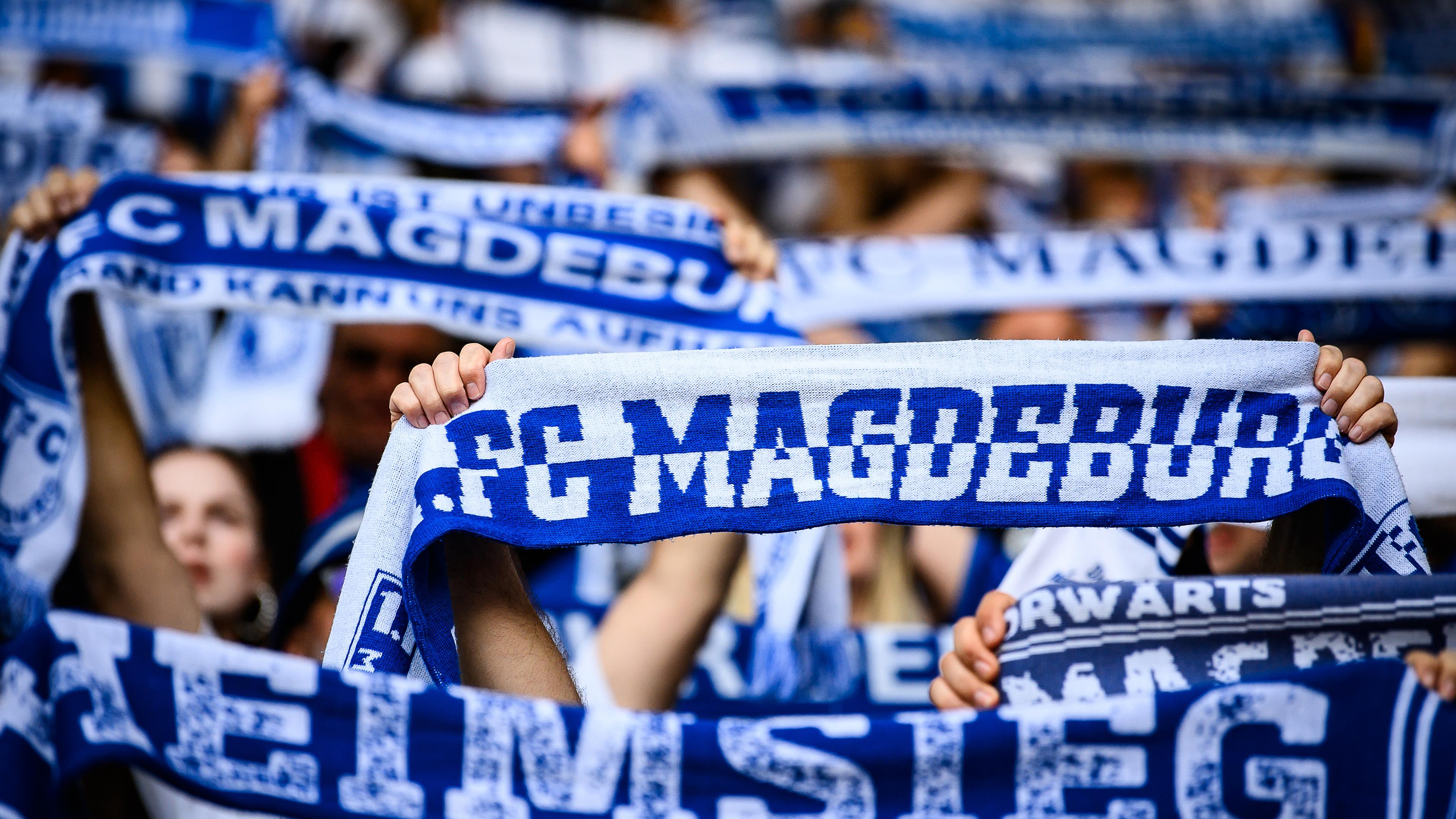 Fans des 1. FC Magdeburg halten ihre Fan-Schals hoch.