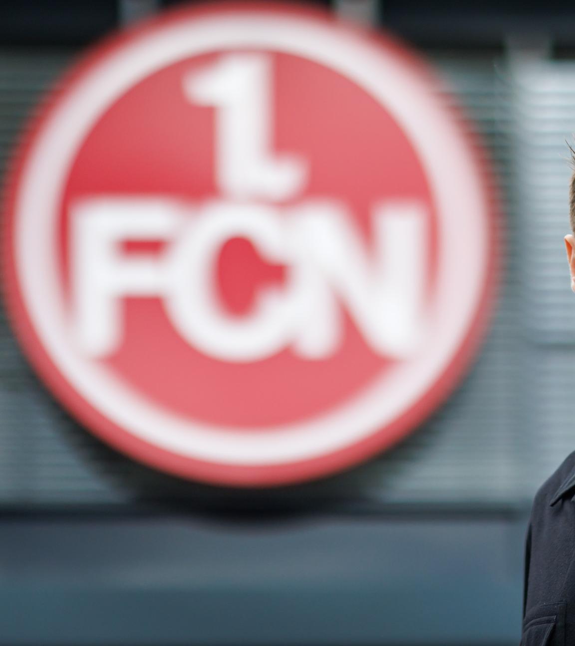 Der neue Trainer Miroslav Klose steht vor dem Vereins-Logo des 1. FC Nürnberg