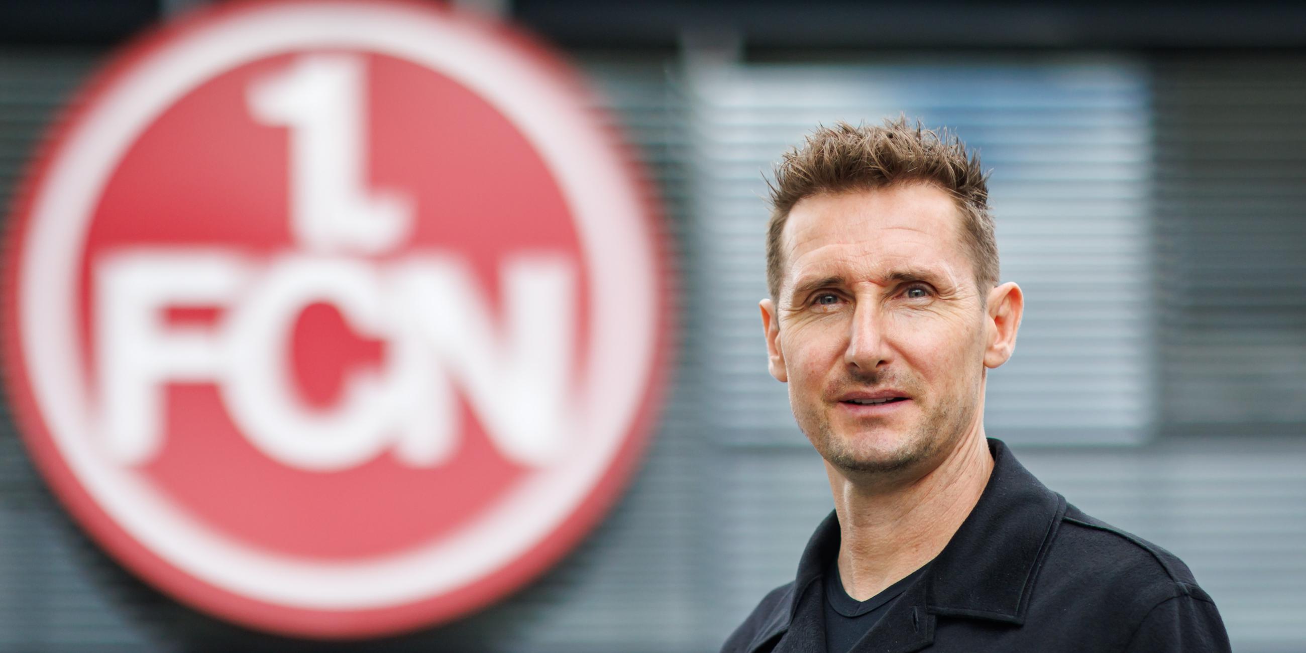 Der neue Trainer Miroslav Klose steht vor dem Vereins-Logo des 1. FC Nürnberg