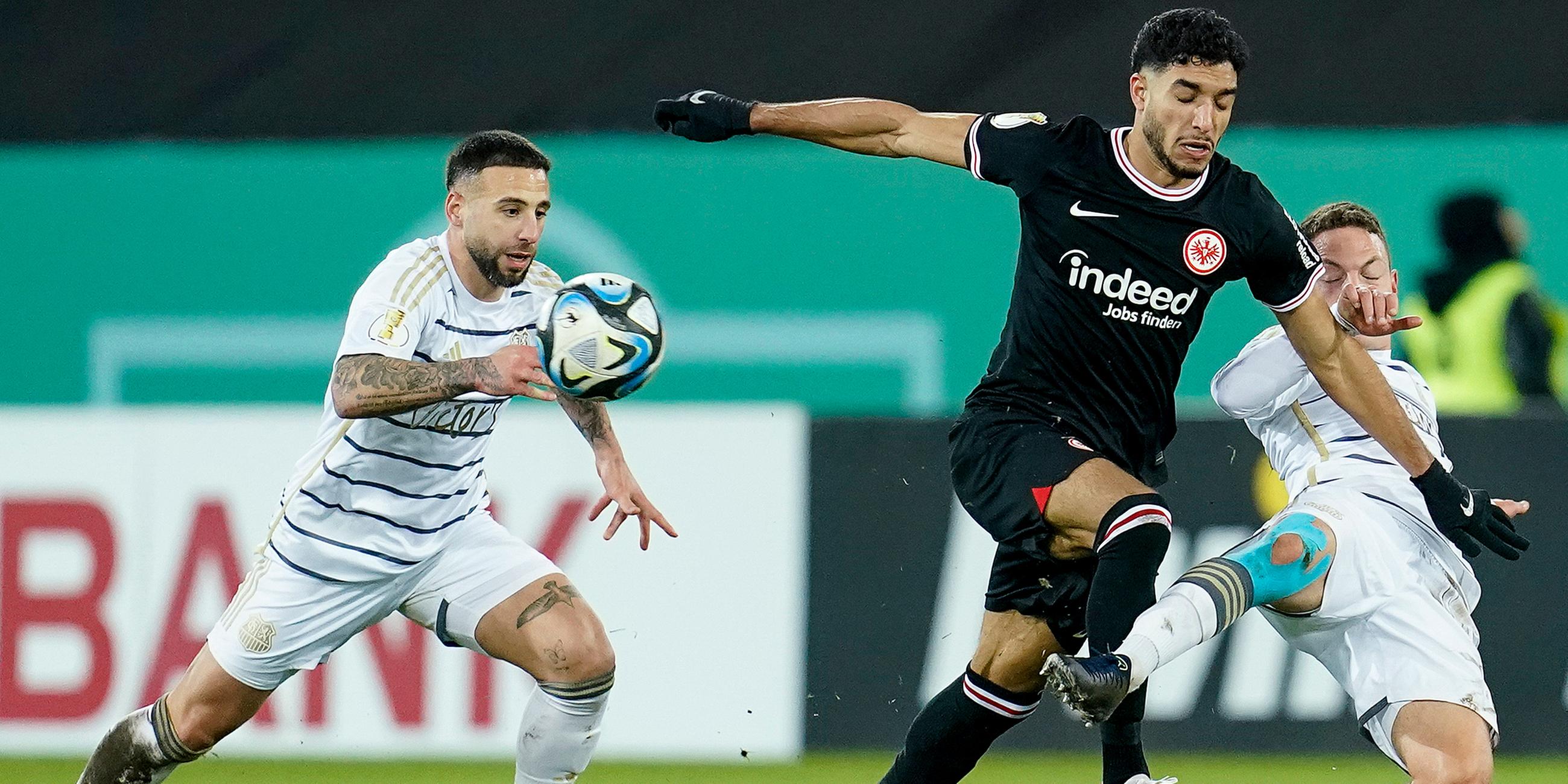  Saarbrückens Calogero Rizzuto (l-r), Frankfurts Omar Marmoush und Saarbrückens Patrick Sontheimer kämpfen um den Ball.