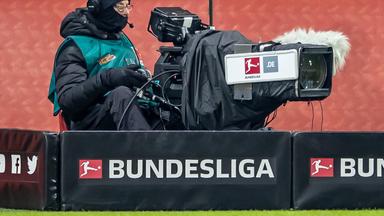 Ein Kameramann hinter einer Kamera bei einem Fußballspiel mit Schriftzug "Bundesliga"