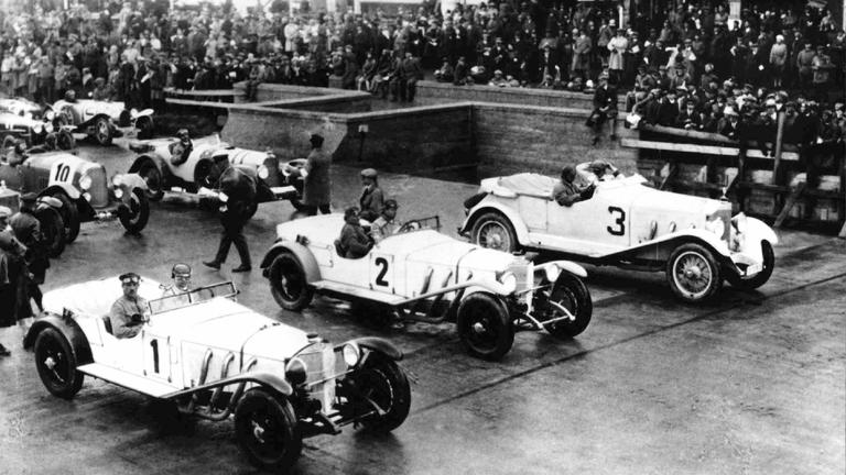 In der ersten Startreihe des ersten Sportwagenrennens (bis 5000 ccm) auf dem Nürburgring warten am 19.6.1927 der spätere Sieger Rudolf Caracciola auf Mercedes-Benz 680 S (Nr. 1), Adolf Rosenberger (Nr. 2) und Rittmeister von Mosch (Nr. 3) auf den Start.