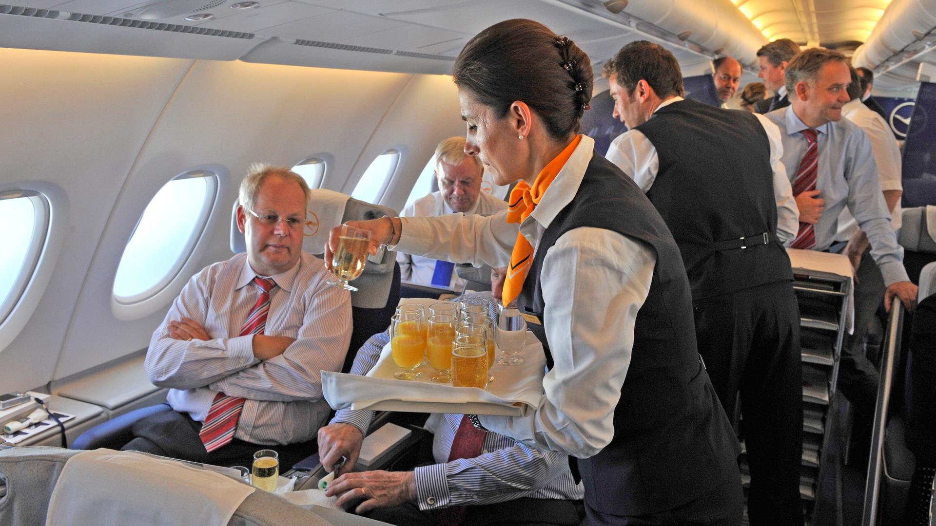 stewardess der lufthansa serviert getraenke im flugzeug