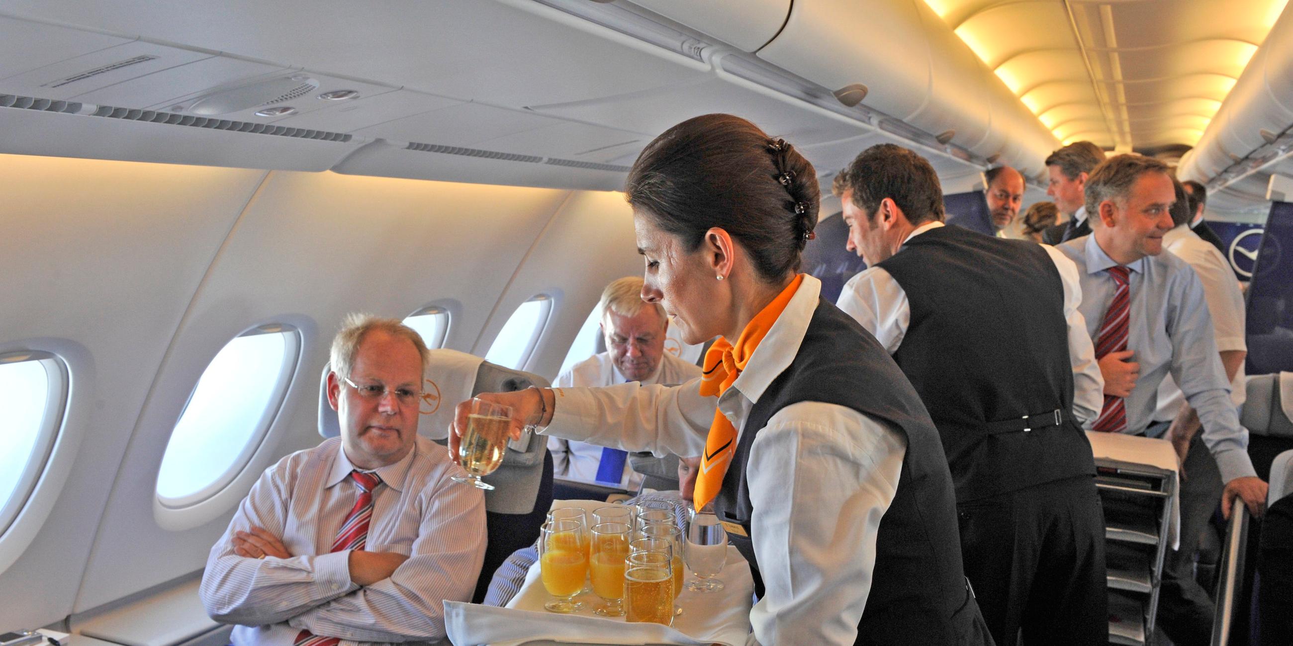 stewardess der lufthansa serviert getraenke im flugzeug