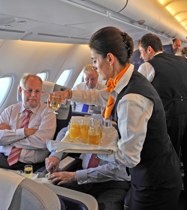 stewardess der lufthansa serviert getraenke im flugzeug