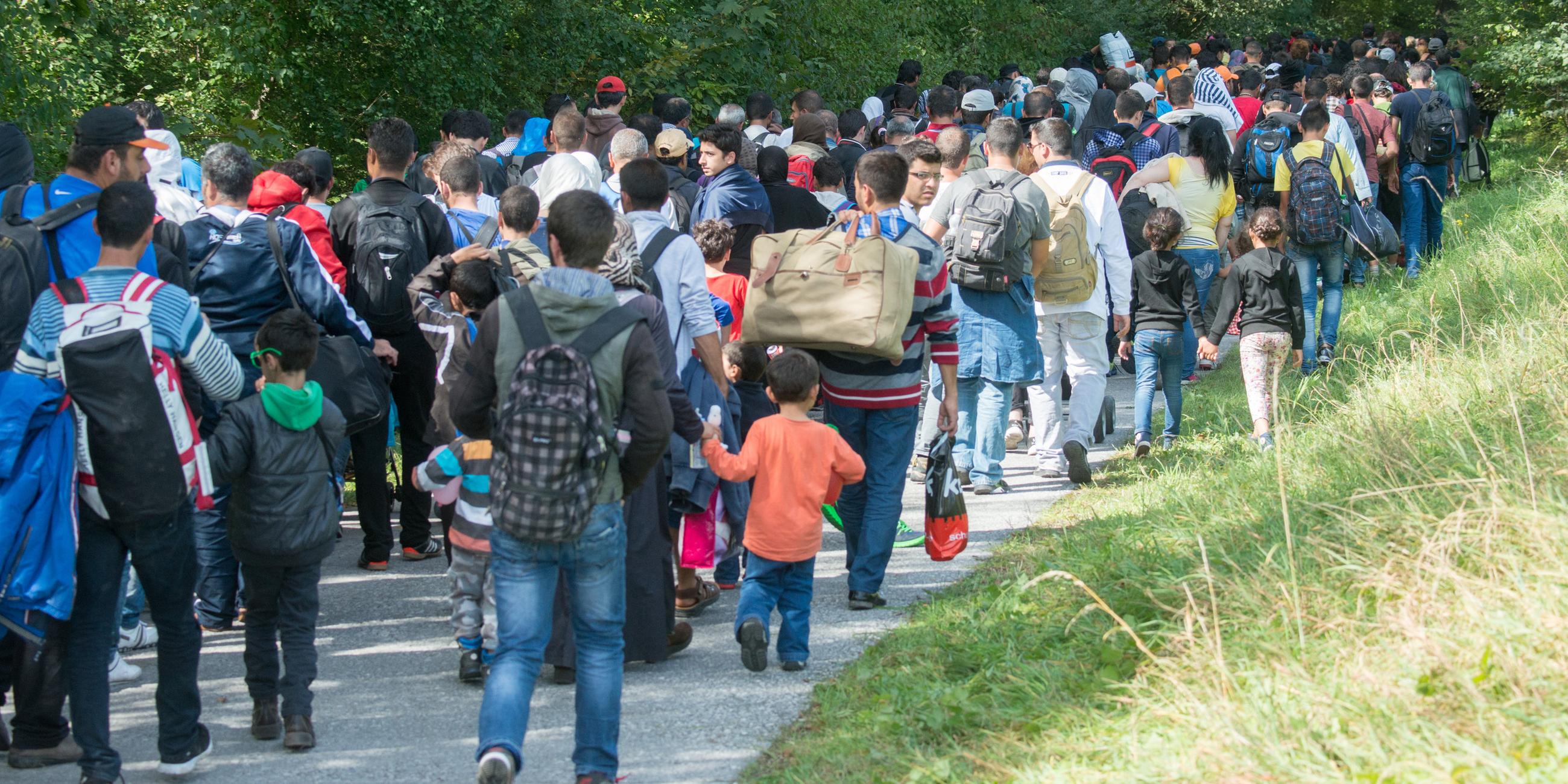 Flüchtlinge gehen am 16.09.2015 hinter der deutsch-österreichischen Grenze zwischen Salzburg und Deutschland nach Freilassing (Bayern) weiter in Richtung Deutschland.