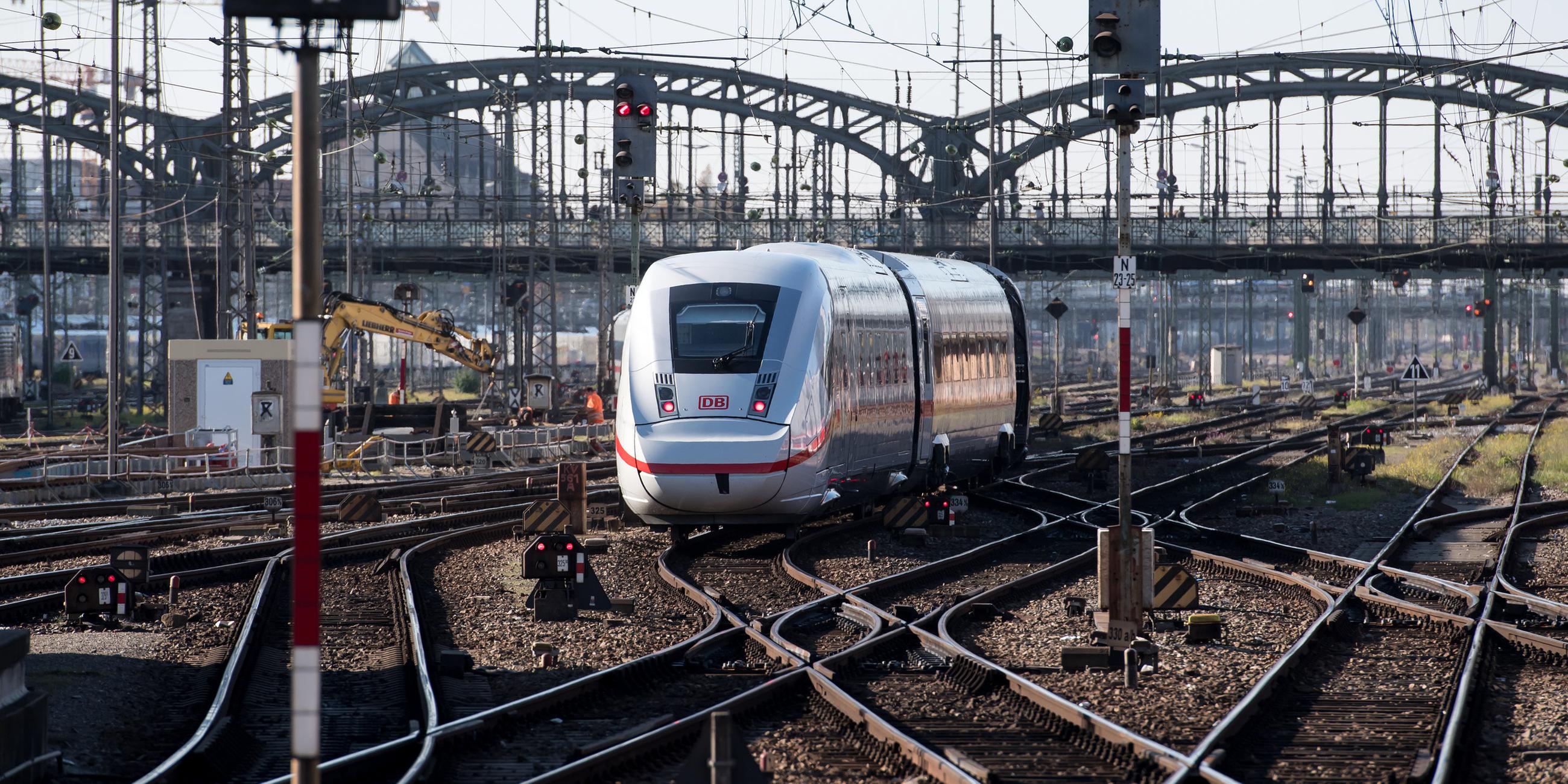 Ein ICE fährt über Gleise mit vielen Weichen, im Hintergrund eine Brücke sowie eine Baustelle