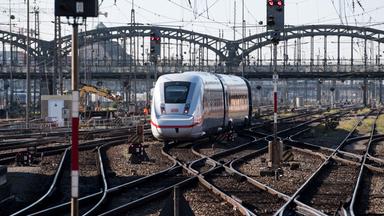 Ein ICE fährt über Gleise mit vielen Weichen, im Hintergrund eine Brücke sowie eine Baustelle