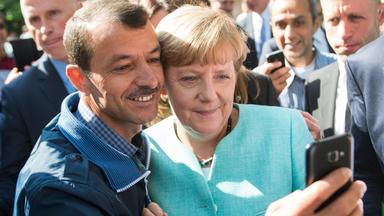 Merkel macht ein Selfie mit einem Flüchtling