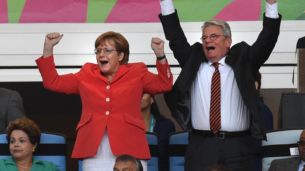 Das Bild zeigt Angela Merkel und den damaligen Bundespräsidenten Joachim Gauck jubelnd bei einem Fußballspiel.
