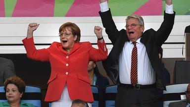 Das Bild zeigt Angela Merkel und den damaligen Bundespräsidenten Joachim Gauck jubelnd bei einem Fußballspiel.