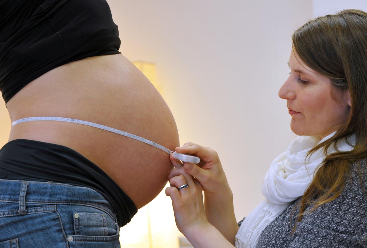 Hebamme misst Bauchumfang einer Schwangeren