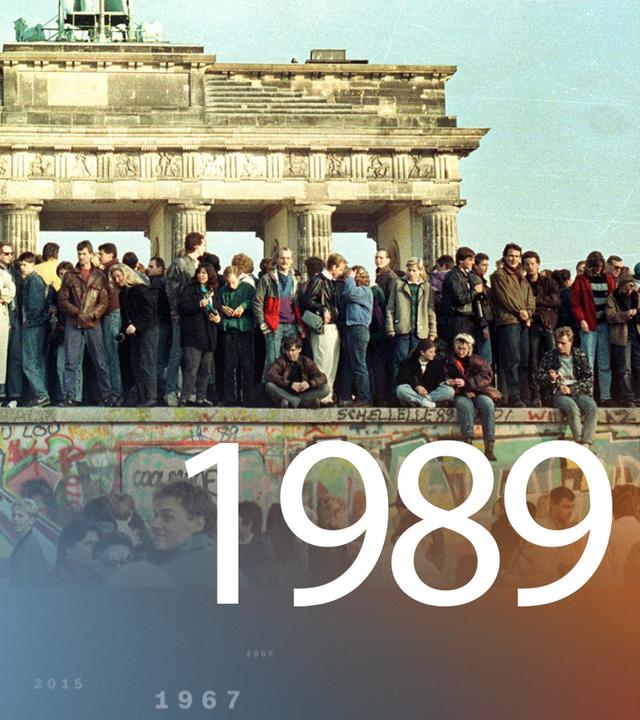 Menschen stehen auf der Berliner Mauer.