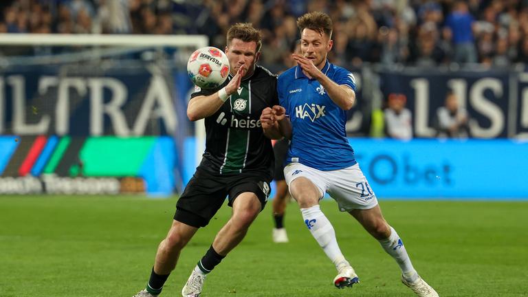 Benjamin Kaellman (Hannover 96) und Matthias Bader (SV Darmstadt 98) im Zweikampf am 11.04.2026 in Darmstadt.