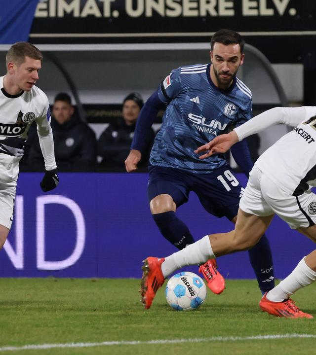 Schalkes Kenan Karamankämpft um den Ball gegen Lukas Pinckert und Elias Baum vom SV Elversberg.