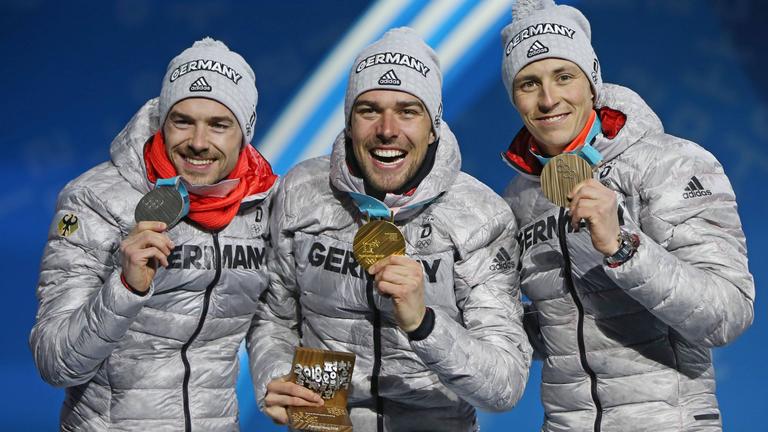 Die deutschen Nordischen Kombinierer Fabian Rießle, Johannes Rydzek und Eric Frenzel (v.l.) jubeln auf dem Podium bei den Olympischen Winterspielen 2018 in Pyeongchang