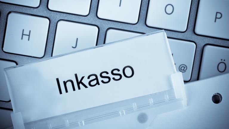 Der eine hängende Ordnertab vor einer Computertastatur bei der Schuldeninkasso