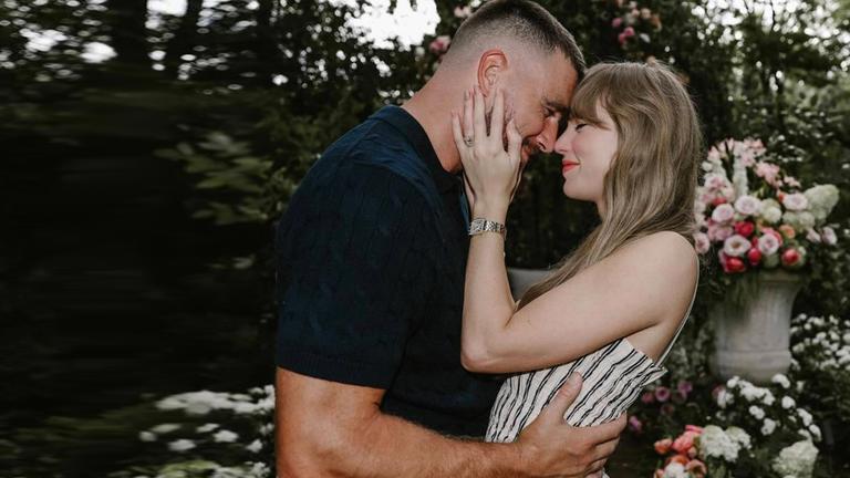 "Das Jahr der Stars 2025": Travis Kelce und Taylor Swift stehen sich im Garten vor einem Blumenbeet nah gegenüber. Sie haben die Stirn aneinander gelegt, Taylor Swift hält den Kopf von Travis Kelce, dieser hält Taylor Swift in der Taille.