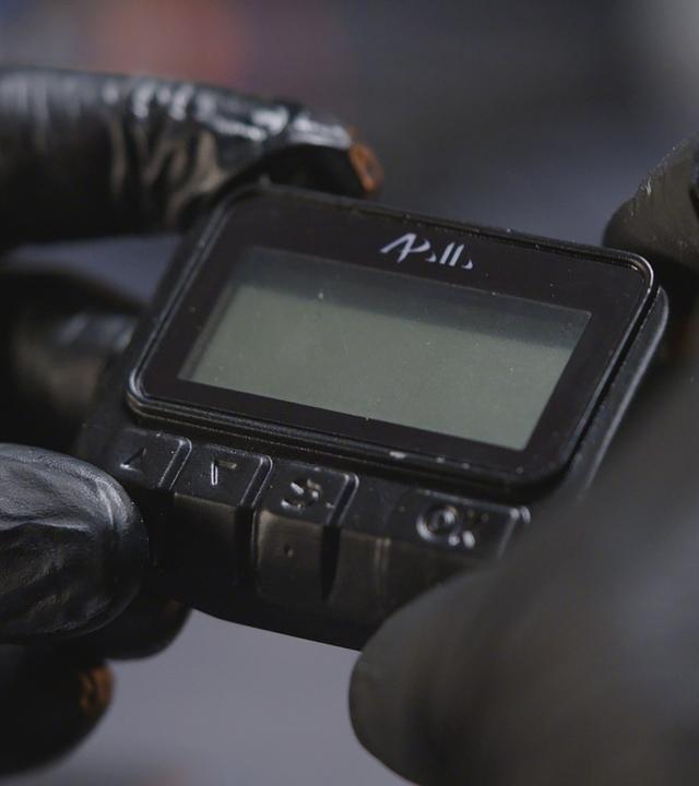"frontal-Dokumentation: Operation Apollo - Die Pager Attacke des Mossad": Nachgestellte Szene, Nahaufnahme: Zwei Hände in Handschuhen halten einen Pager.