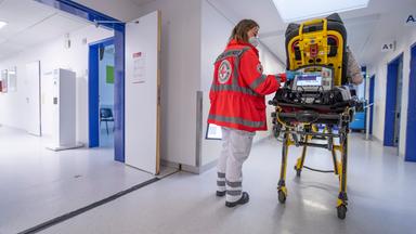 Eine Sanitäterin schiebt eine Patientin über den Krankenhausflur