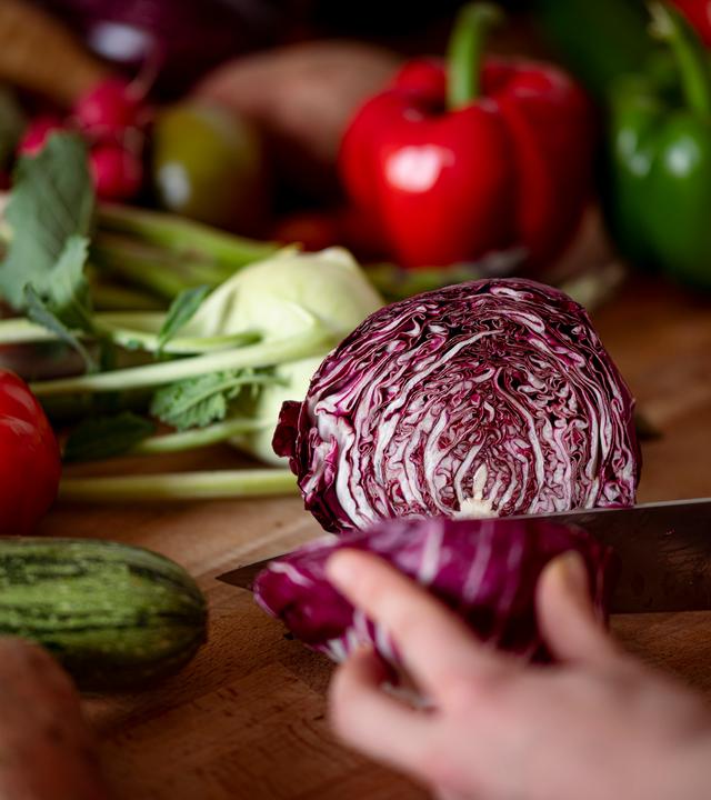 Eine Frau schneidet auf einem Schneidbrett mit einem Küchenmesser einen Radicchio
