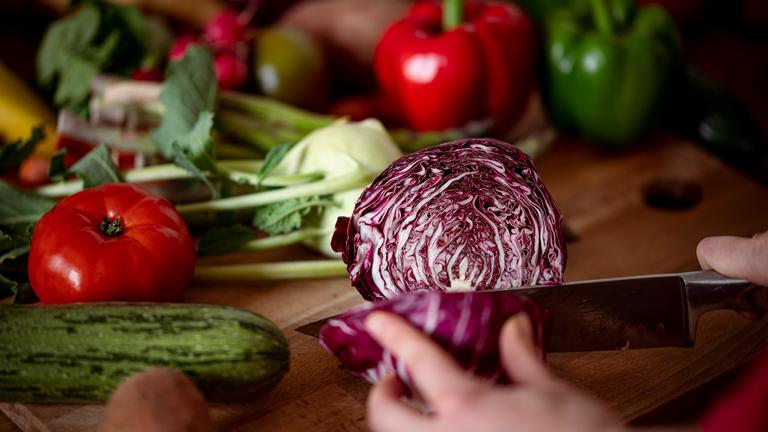 Eine Frau schneidet auf einem Schneidbrett mit einem Küchenmesser einen Radicchio