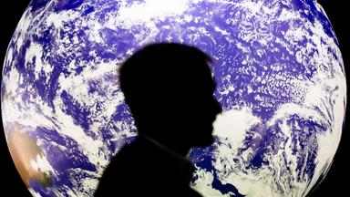 Mann sitzt bei UN-Klimakonferenz COP26 vor einem leuchtenden Globus
