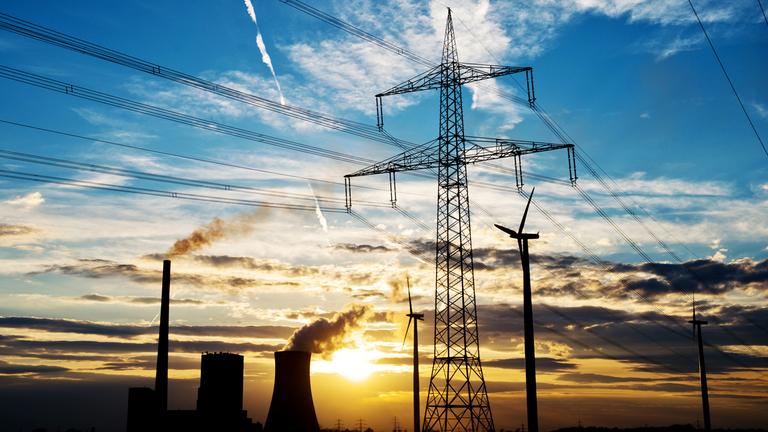 Fossiles Kraftwerk und Windkraftanlage im Sonnenuntergang