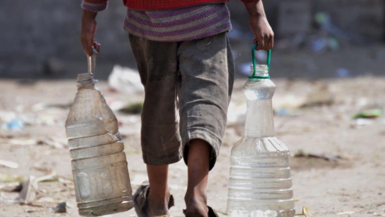 Junge schleppt Wasserkanister