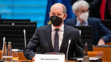 02.02.2022, Berlin: Olaf Scholz sitzt an einem Tisch, davor ein Schild mit seinem Namen