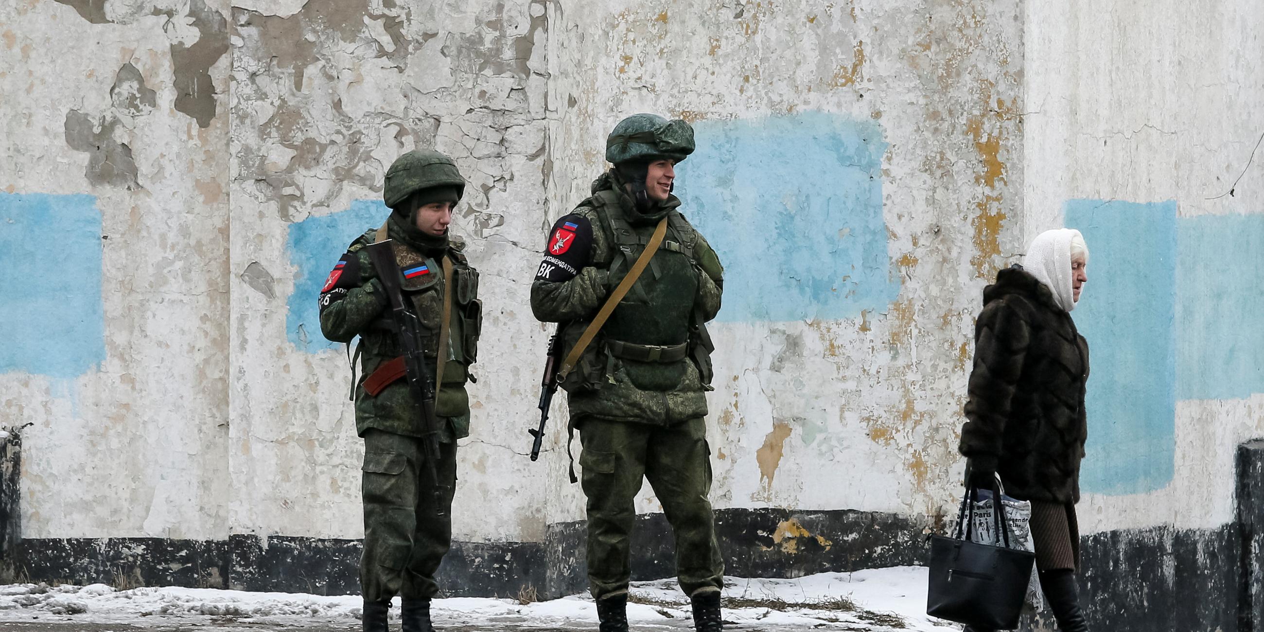 22.01.2022, Ukraine: Eine Dame passiert Militanten der selbsternannten Volksrepublik Donezk.