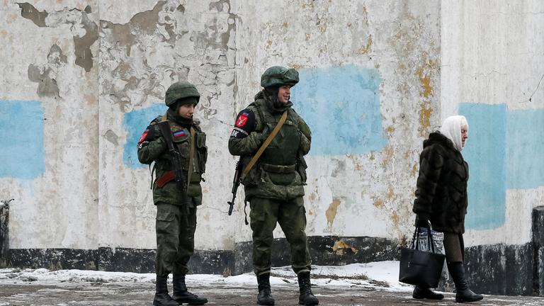 22.01.2022, Ukraine: Eine Dame passiert Militanten der selbsternannten Volksrepublik Donezk.