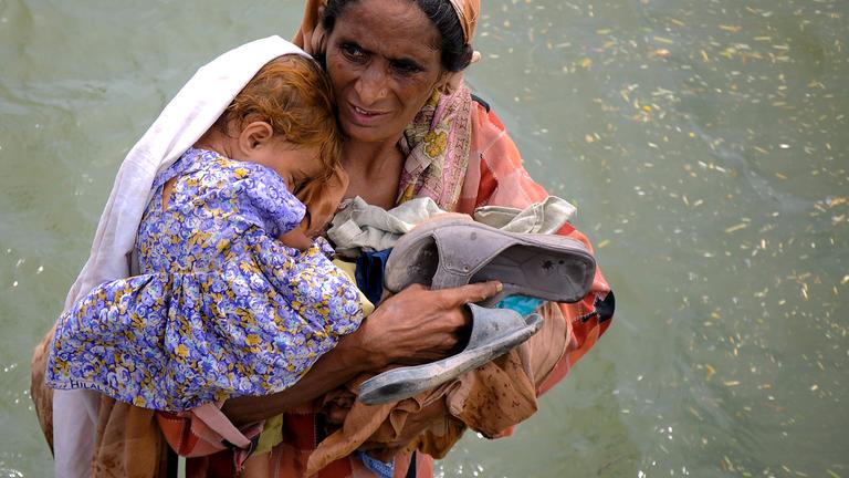 Frau mit Kind in Hochwasser in Pakistan