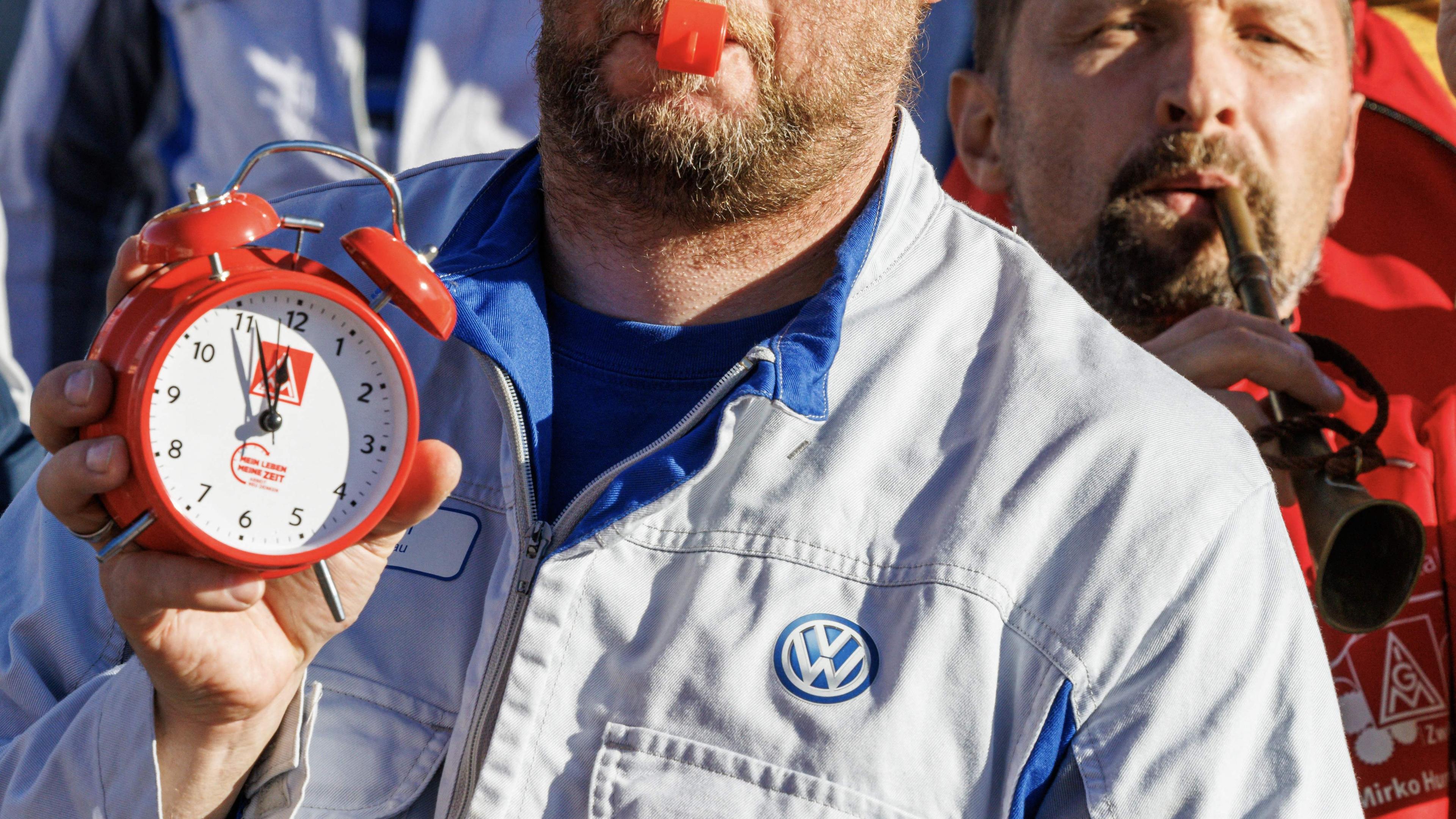 Ein Mitarbeiter des Volkswagen (VW)-Werks in Zwickau hält eine rote Uhr, die auf fünf vor zwölf steht und symbolisiert, dass es Zeit ist“. Er demonstriert auf dem Werksgelände während einer Informationsveranstaltung des Betriebsrats von Volkswagen Sachsen in Zwickau, Ostdeutschland, am 28. Oktober 2024.