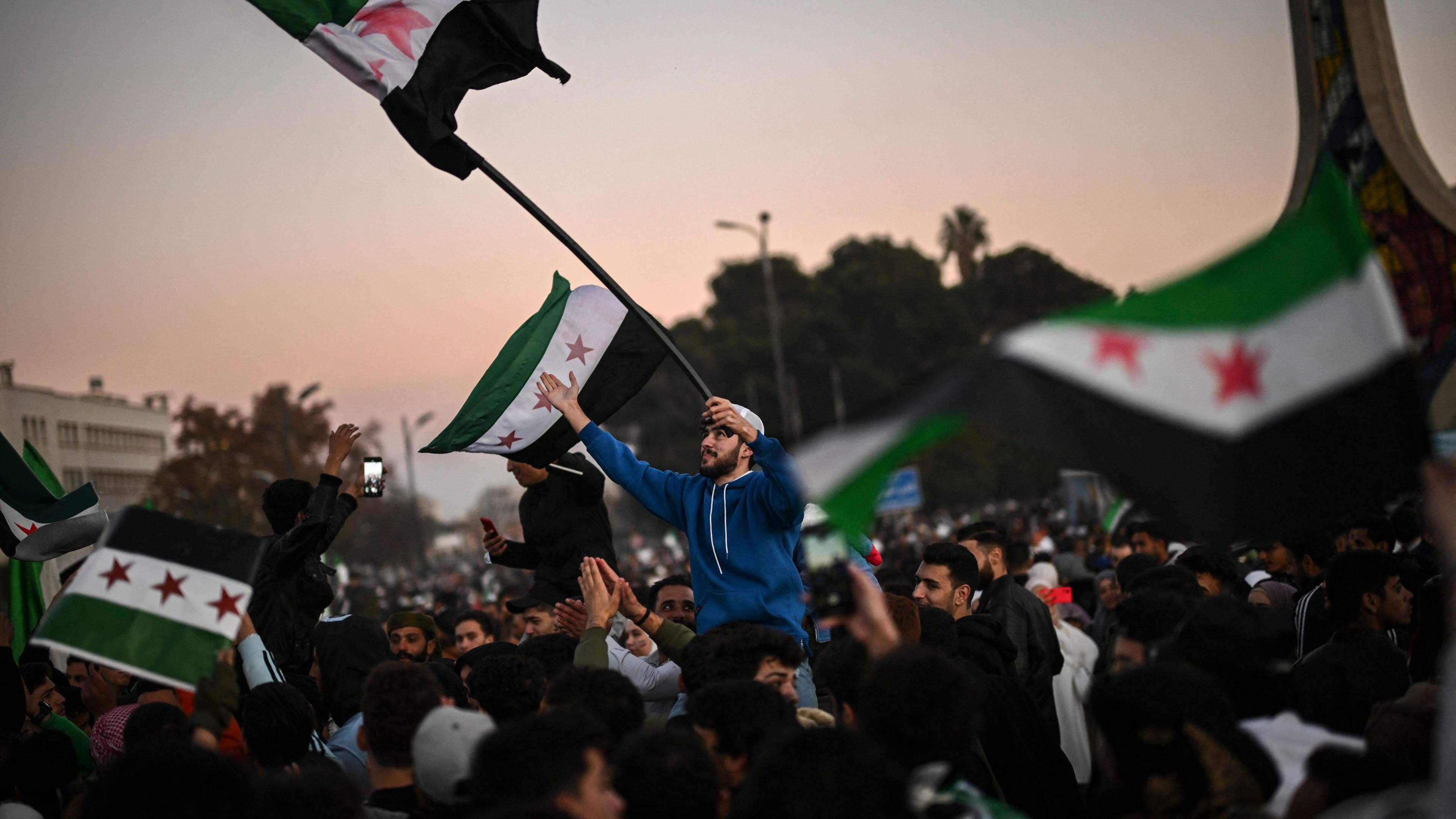 Syrians celebrate the fall of Bashar al-Assad's rule at the main Ummayad square in Damascus, on December 13, 2024. Thousands of jubilant people rallied in central Damascus and in cities across Syria to celebrate during the first Friday prayers since the ouster of president Bashar al-Assad