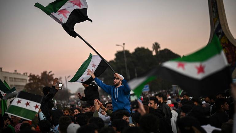 Syrians celebrate the fall of Bashar al-Assad's rule at the main Ummayad square in Damascus, on December 13, 2024. Thousands of jubilant people rallied in central Damascus and in cities across Syria to celebrate during the first Friday prayers since the ouster of president Bashar al-Assad