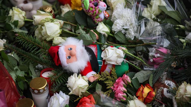 TOPSHOT - A Santa Claus figure is seen among flowers and candles near the site of a car-ramming attack on a Christmas market in Magdeburg, eastern Germany, on December 21, 2024, resulting in several deaths and dozens of injured. German media reports that the death toll has risen to four over night and up to 200 injured in the attack on December