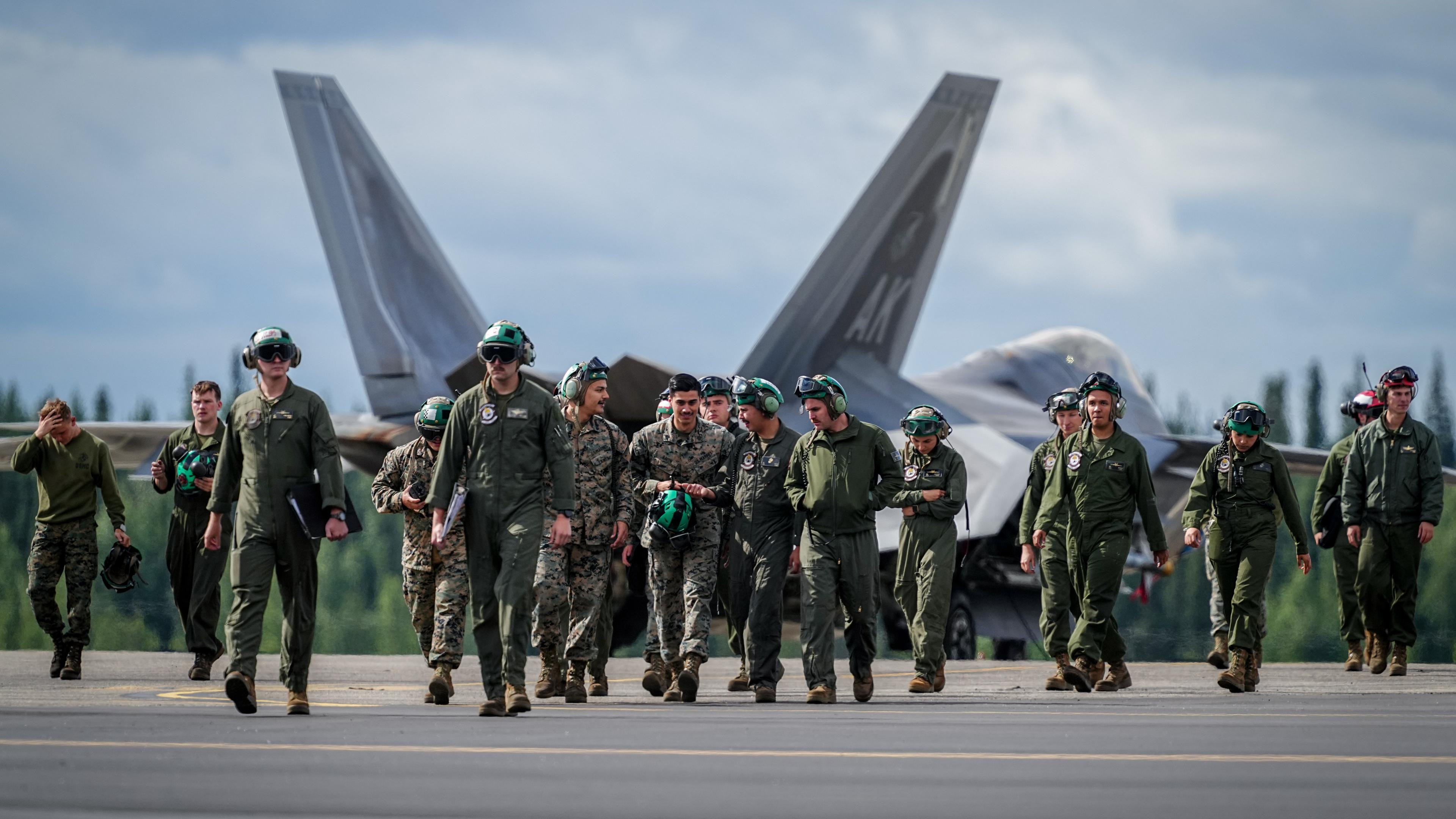 08.07.2024, USA, Fairbanks: US-Soldaten gehen an einem F-22 Kampfjet bei der Nato-Übung ·Arctic Defender 2024· auf der Eielson Air Force Base bei Fairbanks im US-Bundesstaat Alaska vorbei. Eurofighter-Besatzungen aus mehreren Staaten üben gemeinsam mit den USA und unter deutscher Führung in Alaska Luftkriegsoperationen unter Nato-Standards. Angenommen wird dabei ein Angriff auf die Allianz und der Bündnisfall («Artikel 5»).