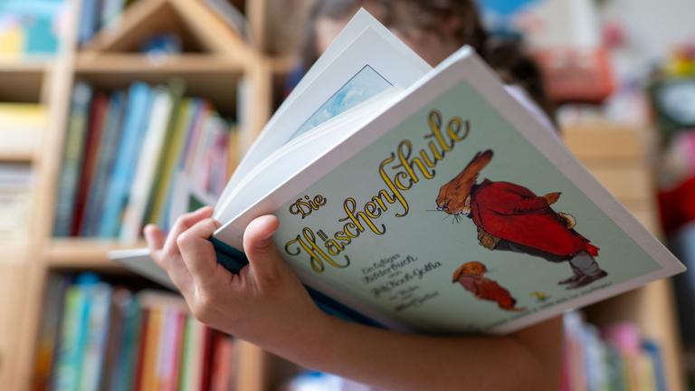 Ein Mädchen hält eine neuere Ausgabe des Kinderbuchs ·Die Häschenschule· (Thienemann-Esslinger Verlag) in ihren Händen. Der Klassiker von Albert Sixtus (1892-1960) wird in diesem Jahr 100 Jahre alt. Sixtus, damals Lehrer im sächsischen Kirchberg, hat die Verse in nur einer Nacht Ende April 1922 niedergeschrieben. Bis zur Veröffentlichung vergingen gut zwei Jahre. Vor 100 Jahren im Spätsommer 1924 erschien die Geschichte dann als Buch mit Illustrationen von Fritz Koch-Gotha