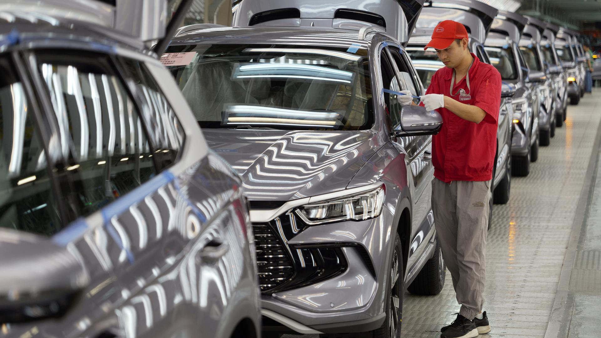 24.04.2024, China, Zhengzhou: Ein Arbeiter prüft die Qualität eines New Energy Vehicle (NEV) im Werk von BYD, Chinas führendem NEV-Hersteller, in Zhengzhou in der zentralchinesischen Provinz Henan.