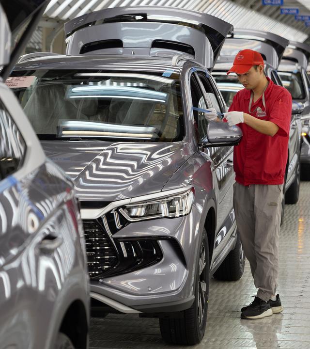 24.04.2024, China, Zhengzhou: Ein Arbeiter prüft die Qualität eines New Energy Vehicle (NEV) im Werk von BYD, Chinas führendem NEV-Hersteller, in Zhengzhou in der zentralchinesischen Provinz Henan.