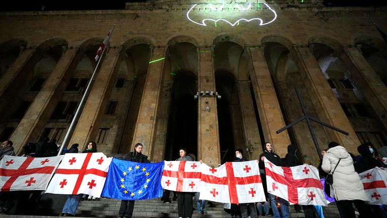 05.12.2024, Georgien, Tiflis: Demonstranten halten georgische und EU-Flaggen während einer Protestkundgebung gegen die Entscheidung der Regierung, die Verhandlungen über den Beitritt zur Europäischen Union auszusetzen.