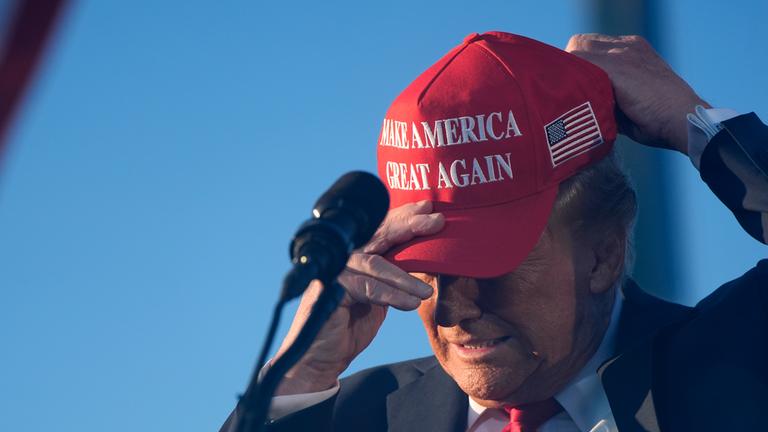 Der republikanische Präsidentschaftskandidat und ehemalige Präsident Donald Trump setzt sich einen Wahlkampfhut auf, während er bei einer Wahlkampfveranstaltung auf der Calhoun Ranch spricht.