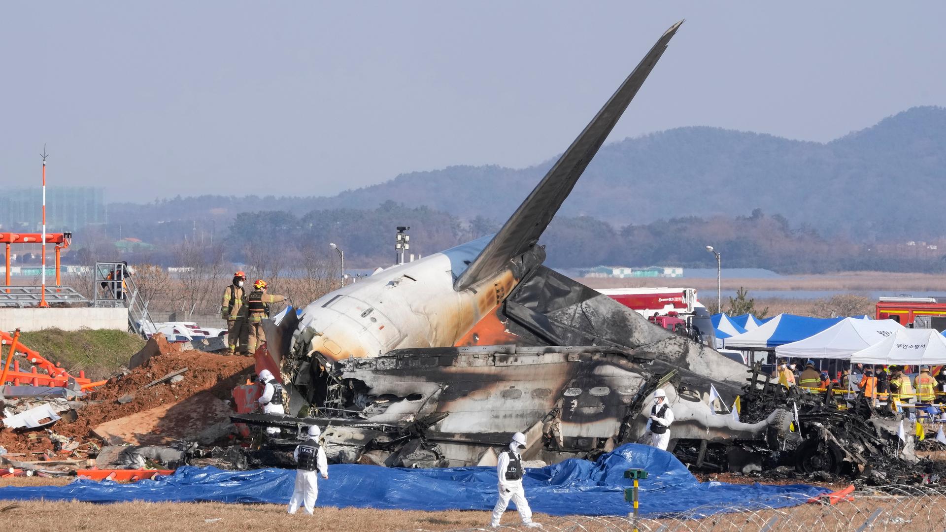 Feuerwehrleute und Mitglieder eines Rettungsteams arbeiten in der Nähe des Wracks eines Passagierflugzeugs am Muan International Airport. Bei der Landung am internationalen Flughafen von Muan in Südkorea ist ein Passagierflugzeug verunglückt.
