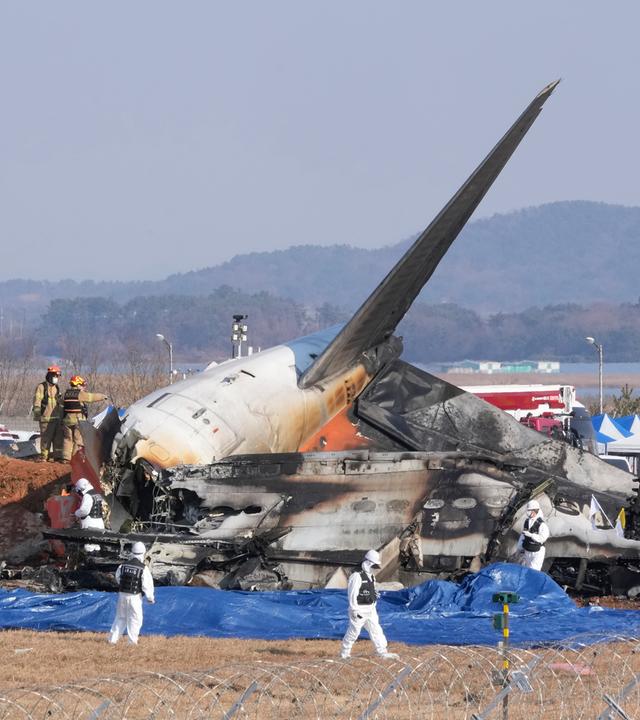 Feuerwehrleute und Mitglieder eines Rettungsteams arbeiten in der Nähe des Wracks eines Passagierflugzeugs am Muan International Airport. Bei der Landung am internationalen Flughafen von Muan in Südkorea ist ein Passagierflugzeug verunglückt.