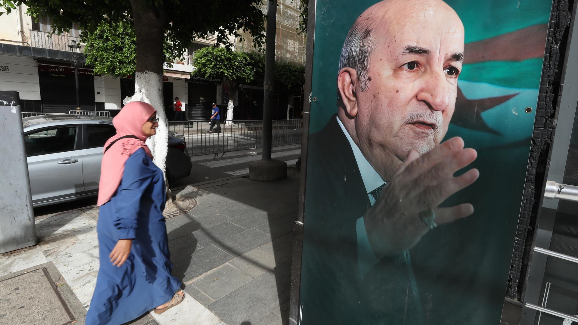 Eine Frau geht an einem Wahlbanner des amtierenden algerischen Präsidenten und des unabhängigen Präsidentschaftskandidaten Abdelmajid Tebboune vorbei, bevor die Präsidentschaftswahlen in Algier, Algerien, am 06. September 2024 stattfinden. Drei Kandidaten, darunter der algerische Präsident Abdelmajid Tebboune, treten bei den Präsidentschaftswahlen am 07. September 2024 an. 